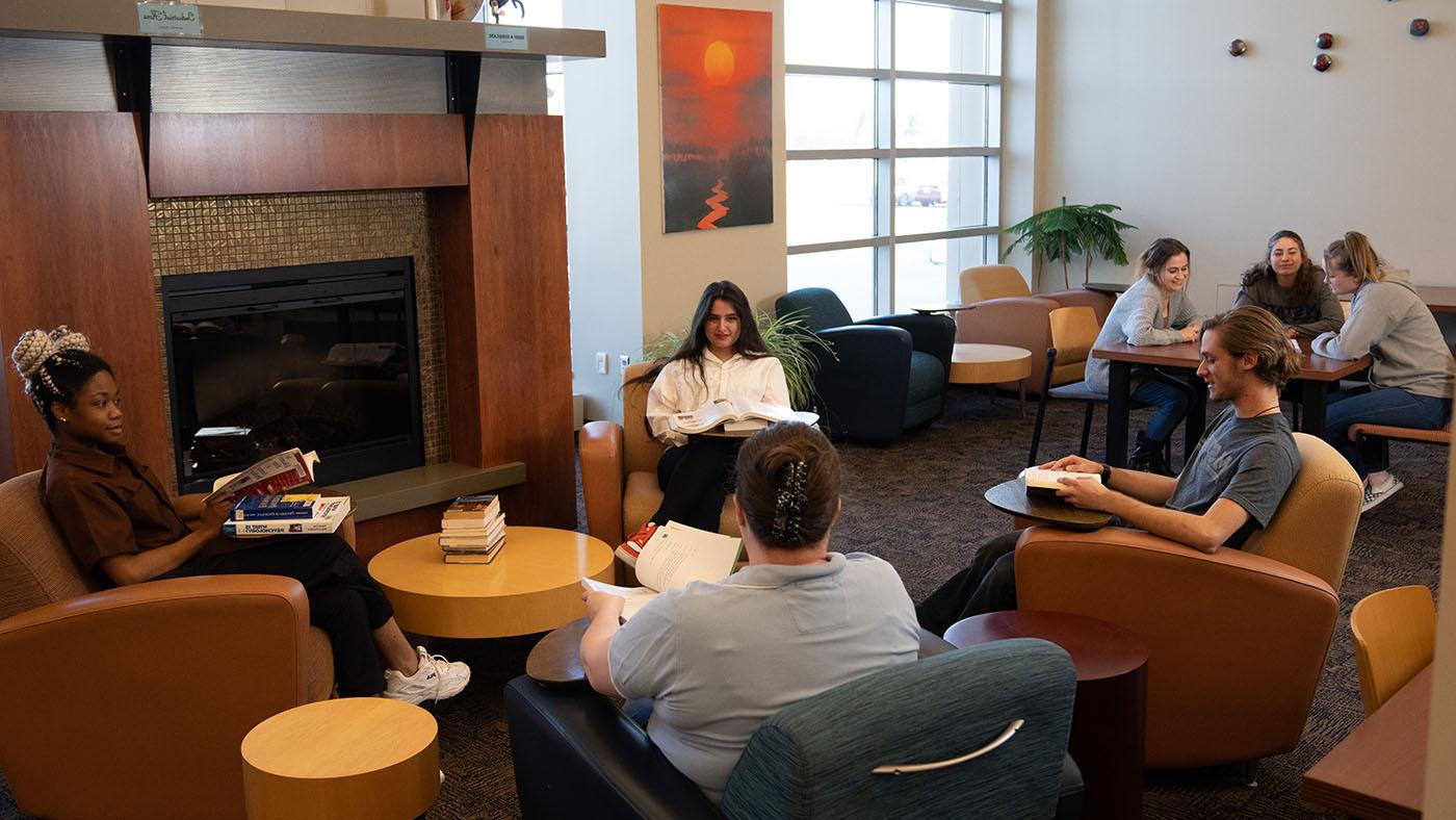 Students sitting by a fireplace talk and study